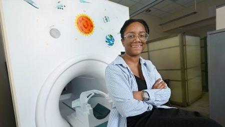 Adrienne Bonar posing next to MRI machine.